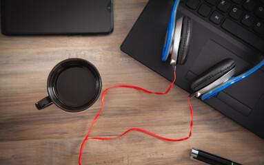 Headphones, coffee, computer keyboard on the wooden desk.
