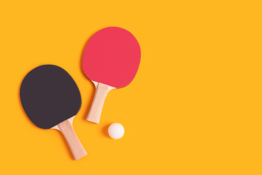 Tennis rackets and white ball on a yellow background. Ping pong concept with copy space.