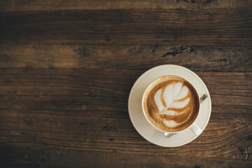White cup with fresh cappuccino on wooden background
