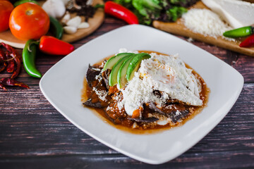 mexican red chilaquiles food with nachos, chicken, egg and cheese traditional breakfast in Mexico	