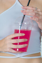 Female hands hold a glass with a cocktail with a straw