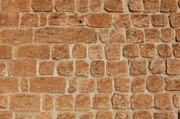 Front view of stone wall background. The stones are light orange in colour.