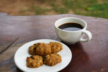 Black coffee cup with cookies on wooden floor, black coffee in the morning to drink with cookies.