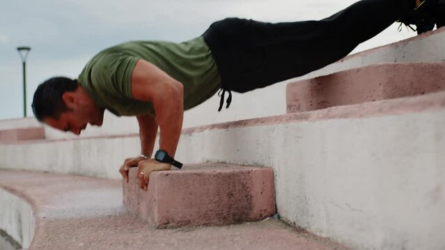 Boy in green t-shirt making push up exercise sport outdoor after rainy day