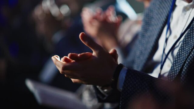 Close Up on Hands of a Crowd of People Clapping in Dark Conference Hall During a Motivational Keynote Presentation. Business Technology Summit Auditorium Room Full of Delegates.