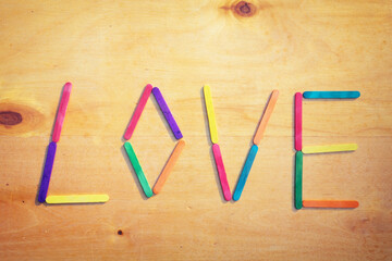 Love text from colorful sticks on brown wooden background