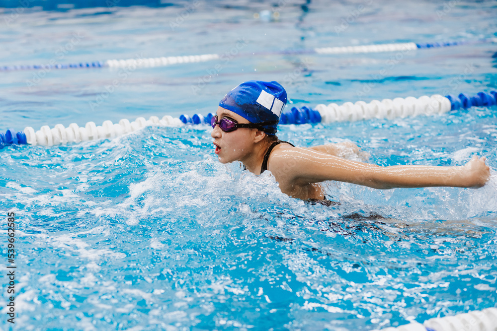 Wall mural hispanic teenager girl swimmer athlete wearing cap and goggles in a swimming training at the pool in