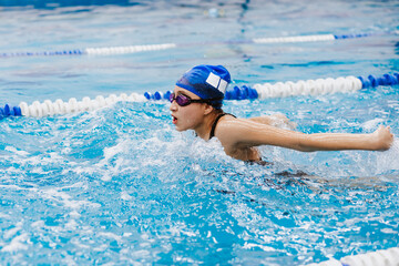 hispanic teenager girl swimmer athlete wearing cap and goggles in a swimming training at the Pool in Mexico Latin America	