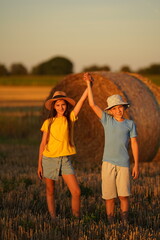 A boy and a girl held hands and triumphantly lifted them up on a summer field.
