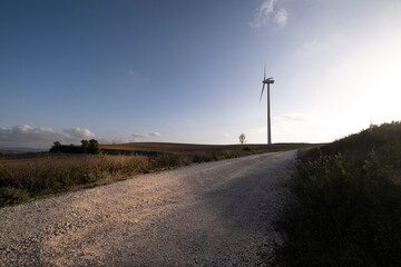 Road in agricultural fields with wind turbines generating clean electricity in Catalonia Spain