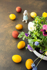 Top view of a vase with beautiful blooming flowers and Easter eggs, cute bunnies, copy space