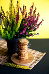 A stack of butter cookies and a colorful decorative plant pot on a yellow and black background