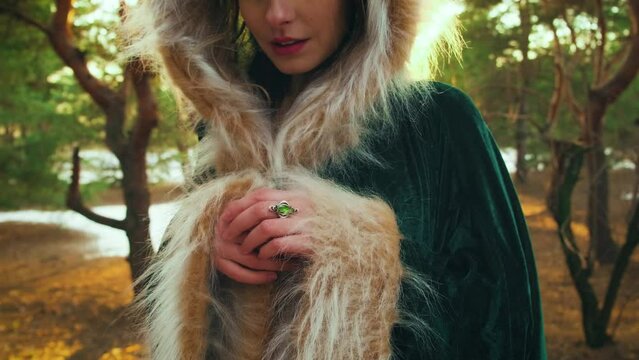 hands close-up, silver vintage old style ring with green emerald stone on female finger. Medieval royal accessories. Portrait woman queen. Princess girl. cape dress hood. snow sun light winter forest