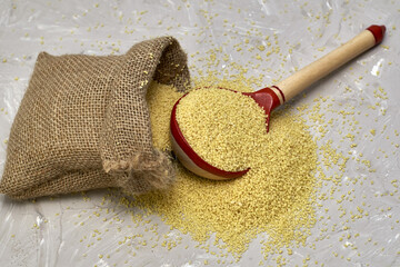 croup couscous spills out of a canvas bag and a wooden spoon on the table