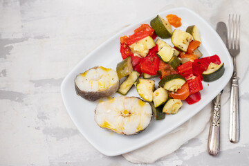 baked vegetables with boiled fish on white plate