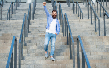 happy bearded guy walk downstairs. full length of guy with beard. hipster guy outdoor at stairs