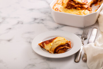 Fresh lasagna with meat and tomato sauce baked in the oven in a ceramic dish.