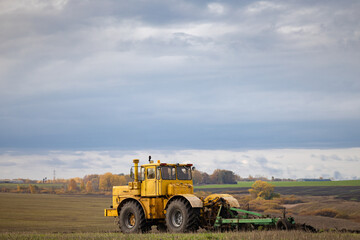 Obraz premium old model tractor working in the field.