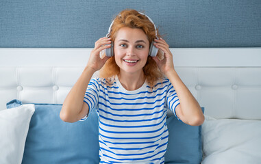 Happy melomaniac woman listening to music on bed, music. Relaxing woman enjoying music