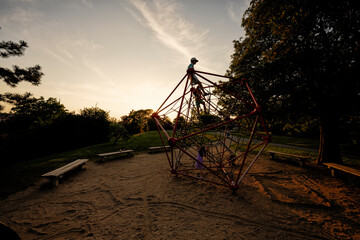 Fototapeta premium Silhouettes of children play in rope polyhedron climb at playground outdoor.