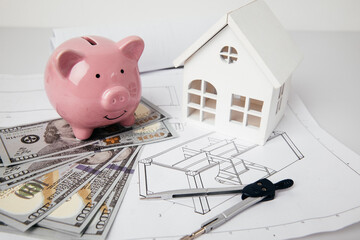 Piggy bank with money, drawings, engineer tools and model of house