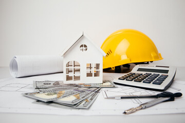 Construction drawings with helmet, money and model of house, cost of building