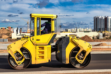 Vibratory road roller lays asphalt on a new road under construction. Close-up of the work of road...