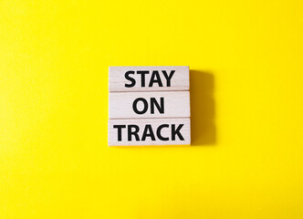 Stay on track symbol. Wooden blocks with words Stay on track. Beautiful yellow background. Businessman hand. Business and Stay on track concept. Copy space