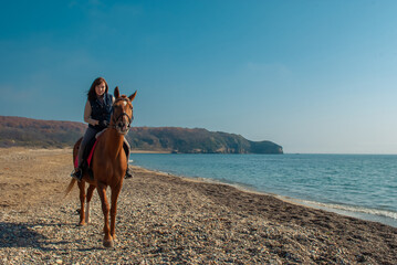 Selective focus. Girl and horse. Horse riding by the sea.