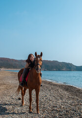 Selective focus. Girl and horse. Horse riding by the sea.