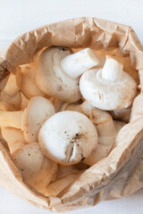 Closed cup mushrooms in a brown paper bag. Eco friendly recycling compostable packaging.