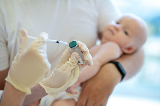 Pediatrician preparing to vaccinate a newborn baby