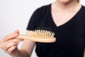 Naklejka premium Unrecognizable woman with hair loss problem holds hairbrush.
