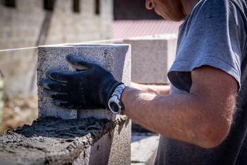 Maçon construisant un mur avec des agglos et du ciment