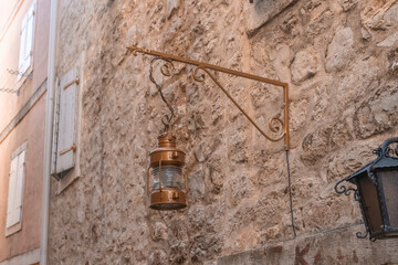 an old street lamp attached to the stone wall of an old building. Old lighting fixtures. An antique lamp