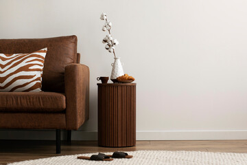 Minimalist composition of elegant and warm space with brown sofa, wooden side tables, decoration,...