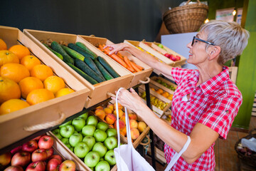 Mature woman buying goods in fruits and vegetables shop.