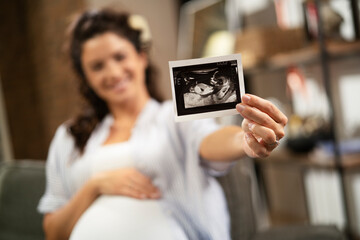 Pregnant woman with ultrasound photo. Beautiful pregnant woman enjoy at home.