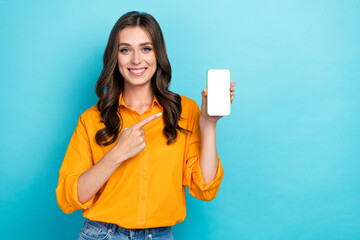 Photo of cheerful pretty person indicate finger empty space telephone display isolated on blue color background