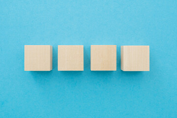 Four wooden cubes, square shape with blank surface on blue background, for business concept ideas