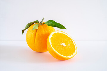 Orange with cut in half and green leaves isolated on white background.