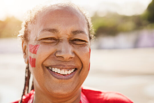 Red african senior sport fan laughing out of the stadium before football match - Focus on face