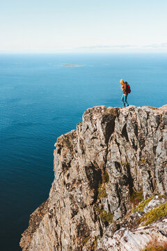 Traveler on mountain cliff hiking in Norway active vacations travel healthy lifestyle adventure outdoor aerial sea view
