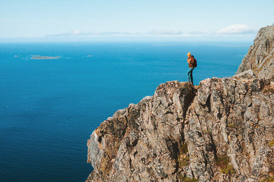 Woman climbing mountain standing on cliff hiking in Norway Travel Lifestyle adventure active vacations outdoor extreme sport