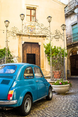 a small old blue car in the narrow streets of the historic old town. cobbled streets and old buildings - obrazy, fototapety, plakaty