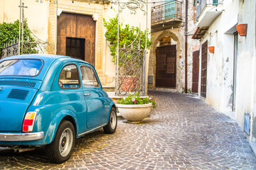 a small old blue car in the narrow streets of the historic old town. cobbled streets and old buildings