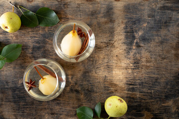 Fototapeta na wymiar Two glasses with a drink with sweet pears stewed in white wine on a wooden table. Festive dessert