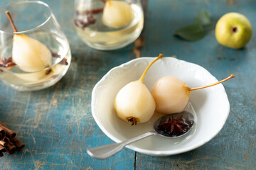 A white plate with delicious pears in wine on a wooden table.