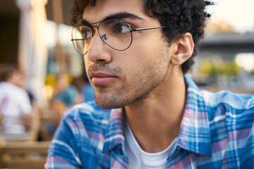 Obraz premium Handsome attractive young teenager sitting at the street in old town, looking away 