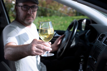 A man with a glass of wine driving a car.